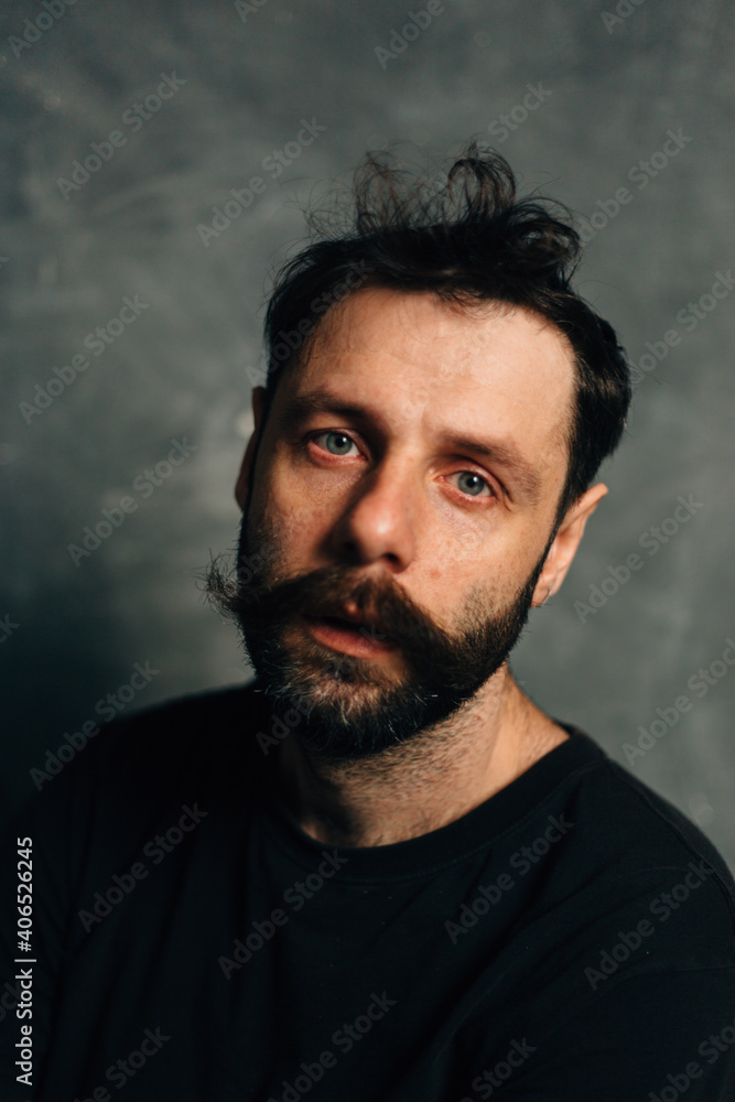 Portrait of a courageous guy with a beard and mustache on a canvas background