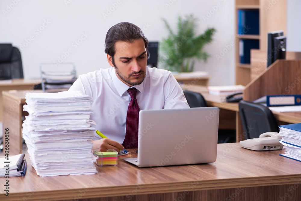 Obraz premium Young male employee unhappy with excessive work in the office