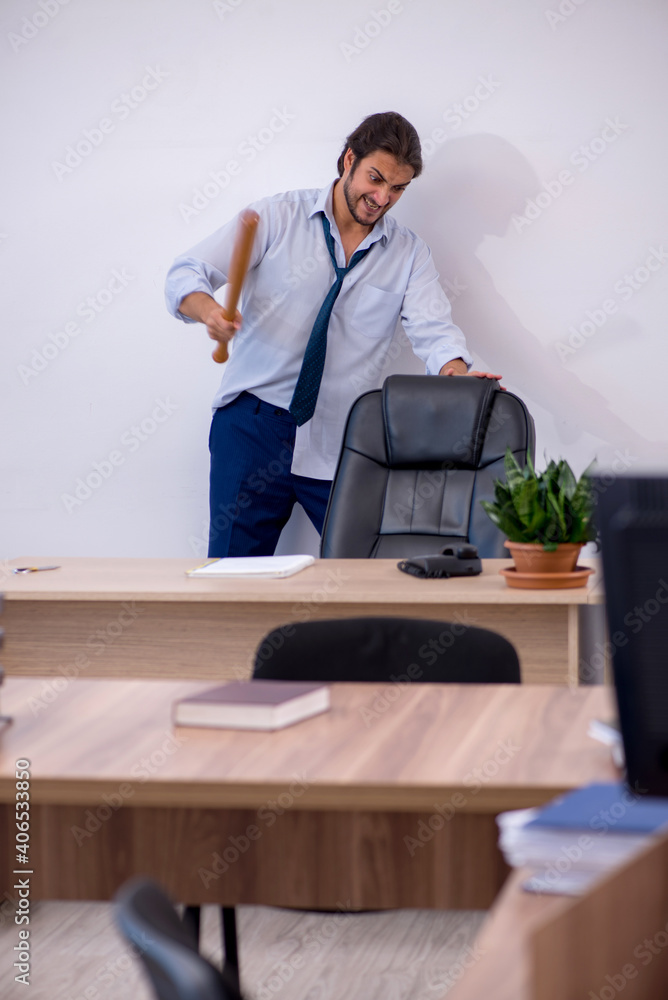 Young male furious employee holding baseball bat in the office Young male furious employee holding baseball bat in the office