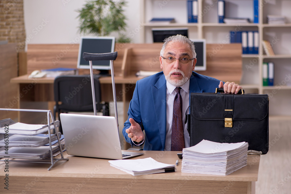 Old businessman employee after accident working in the office Old businessman employee after accident working in the office