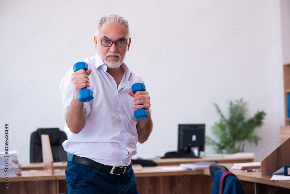 Old businessman employee doing sport exercises in the office