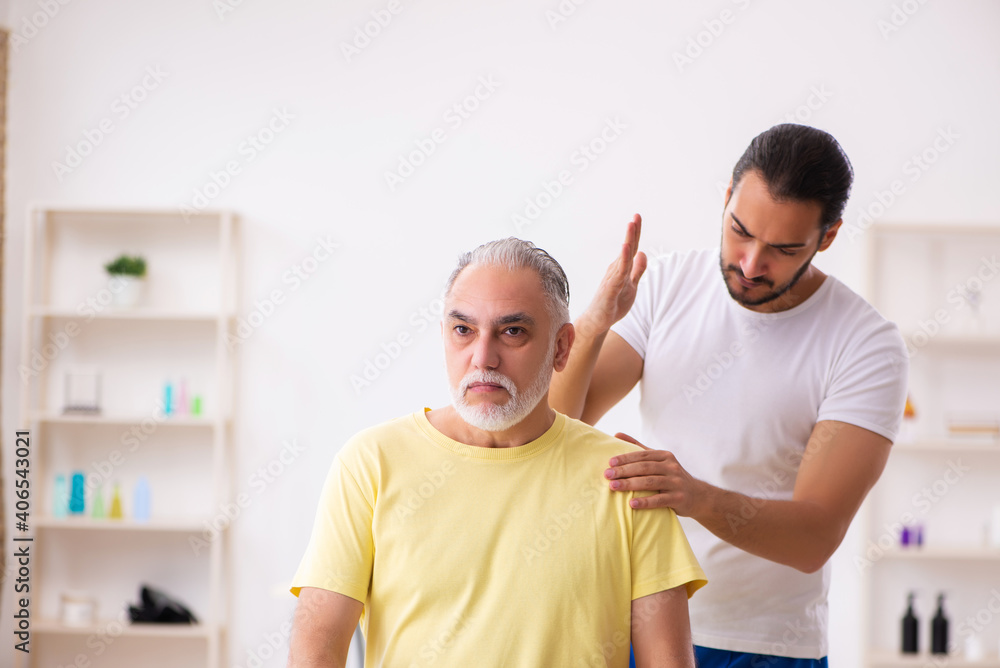 Obraz premium Old male patient visiting young male doctor chiropractor