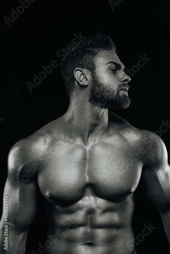 Male fitness model Konstantin Kamynin posing shirtless on black background