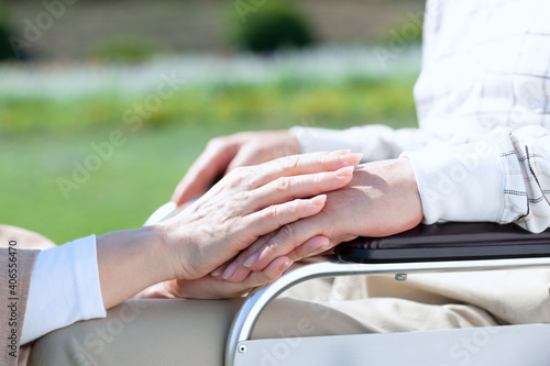 車椅子に乗る男性の手を握る女性