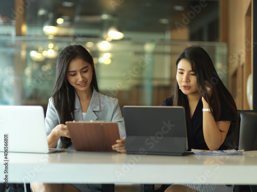 Two businesswomen consulting on their project in office room