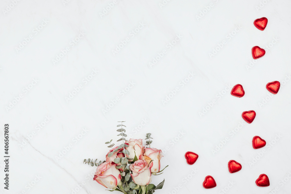 Valentine's rose bouquet with red chocolate hearts on a white marble background