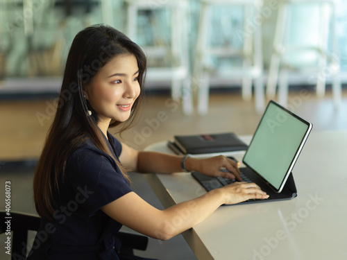 Female office worker working with laptop on the table in office room