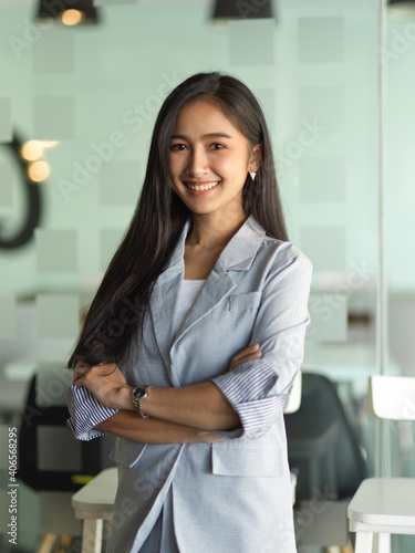 Businesswoman smiling and arms crossed standing in office room