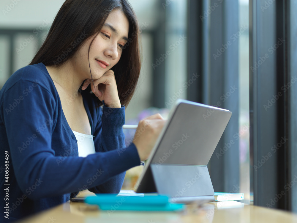 Female student doing assignment with digital tablet and stationery in cafe Female student doing assignment with digital tablet and stationery in cafe