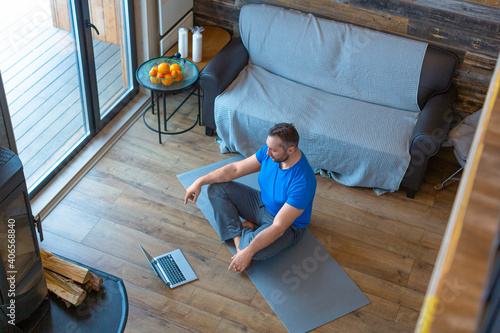 Relaxation and mental health. Man meditates at home in front of a laptop. Onein yoga tutorial. photo