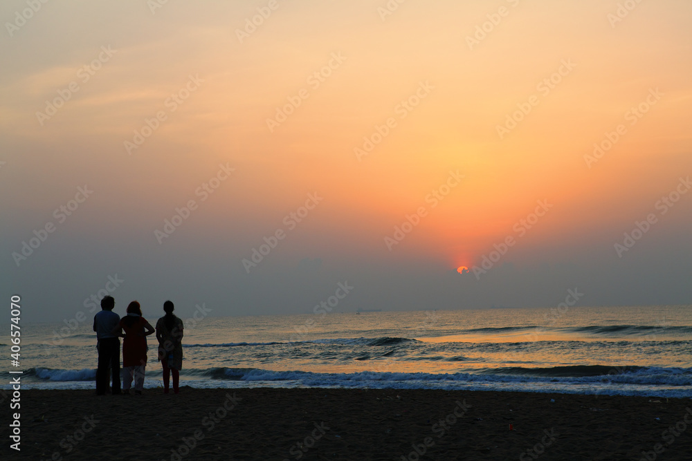 group of people on the beach in sunset.