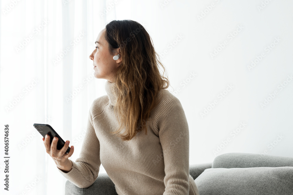 Woman wearing wireless earbuds and using a mobile phone Woman wearing wireless earbuds and using a mobile phone