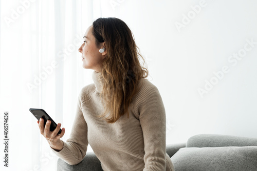 Φωτογραφία Woman wearing wireless earbuds and using a mobile phone