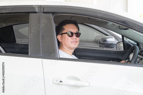 Asian man driving car and wearing dark glasses