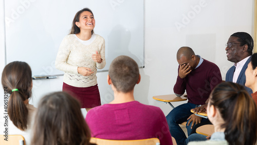 Group of students attentively listening to lecture of female teacher in classroom