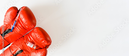 Syringe and dope ampoule on red boxing gloves. Banner, copy space. Doping, pharmacology and sports concept.