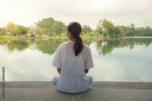 An Asian woman relaxing by the water in a park