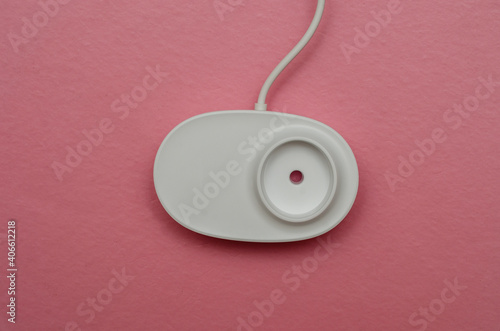 white charger for electric toothbrush on pink background, top view