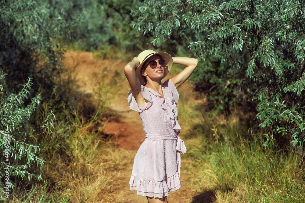 Portrait of a young woman in a straw hat and sunglasses in nature . Beautiful girl on a summer walk Portrait of a young woman in a straw hat and sunglasses in nature . Beautiful girl on a summer walk