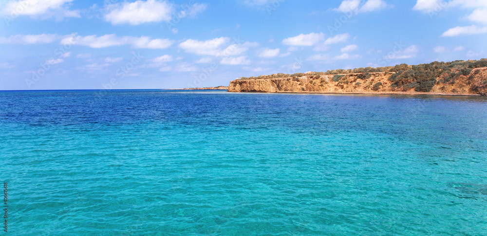View of rocky coast turquoise sea waters on a sunny day with blue sky. Blue lagoon. Destination scenic seascape. Travel and adventure. Cyprus. Mediterranean. No people. Vivid web banner