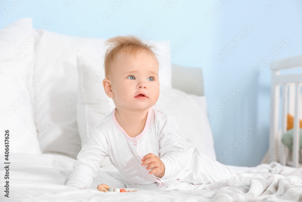 Cute little baby with teething toy sitting on bed Cute little baby with teething toy sitting on bed