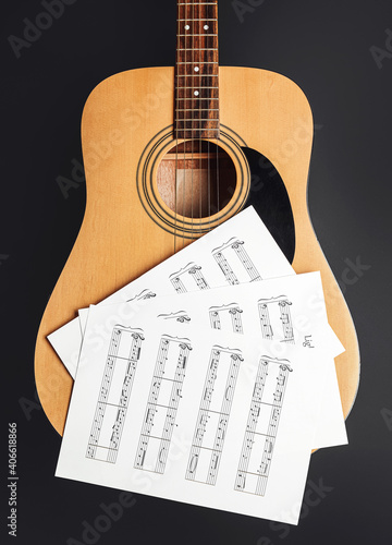 Music sheets and guitar on dark background