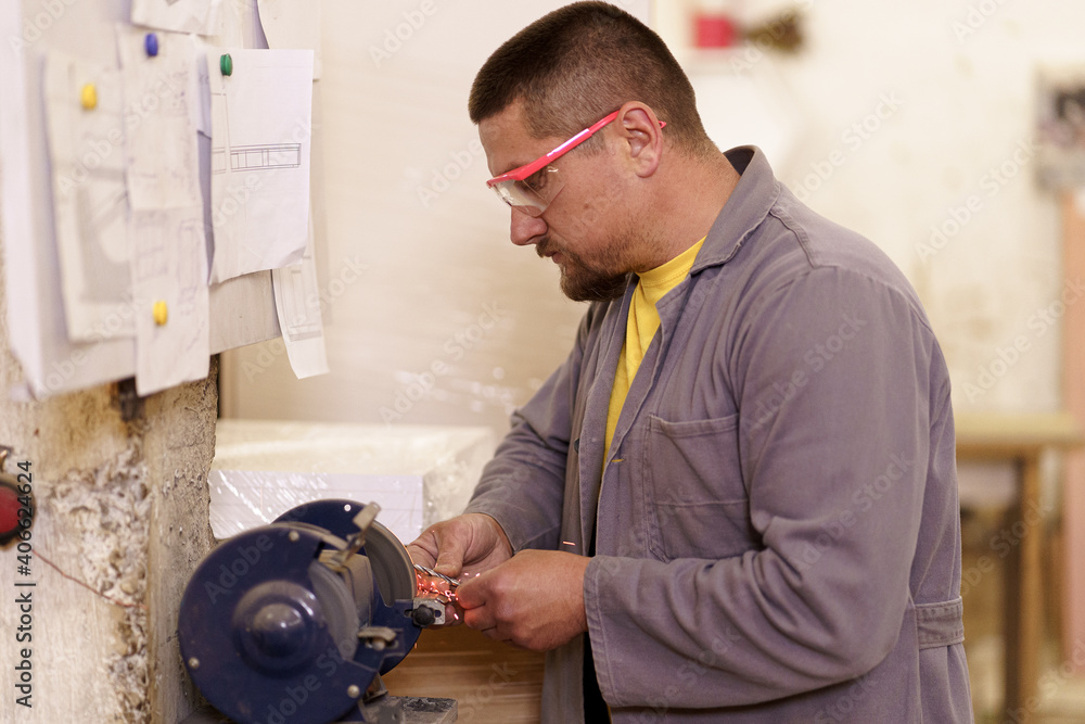 Obraz premium Man hands sharpens a drill at the grinder