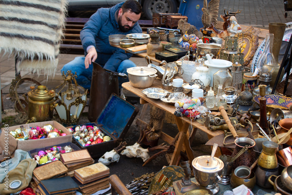 A man buying different antiques on flea market - vintage silver cultery - spoons, knifes, forks and other vintage things. Collectibles memorabilia and garage sale concept, selective focus