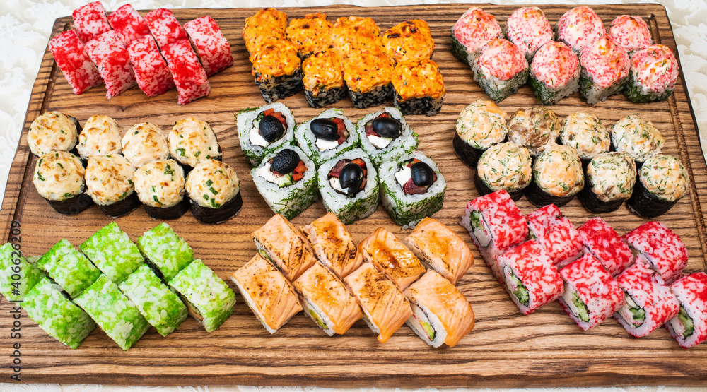 Different types of delicious and juicy sushi and rolls on a wooden board