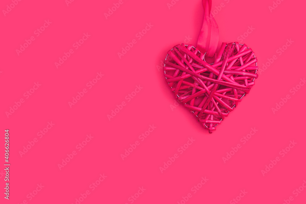 Pink wicker heart symbol lies on the background to Valentine's Day. Top view. Flat lay. Greeting card, concept of the holiday of lovers.