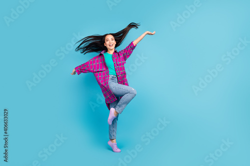 Fototapeta Naklejka Na Ścianę i Meble -  Full body photo of adorable lady dancing have great time wear checkered long shirt isolated on blue color background
