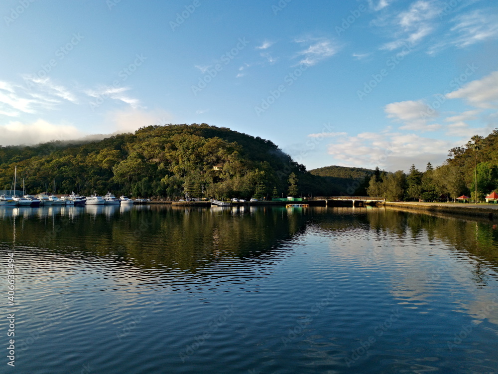 Beautiful morning  panoramic view of a cree with reflections of blue sky, mountains, trees and boats, Bobbin Head, Ku-ring-gai Chase National Park, Sydney, New South Wales, Australia
