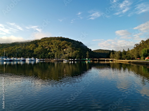 Beautiful morning panoramic view of a cree with reflections of blue sky, mountains, trees and boats, Bobbin Head, Ku-ring-gai Chase National Park, Sydney, New South Wales, Australia 