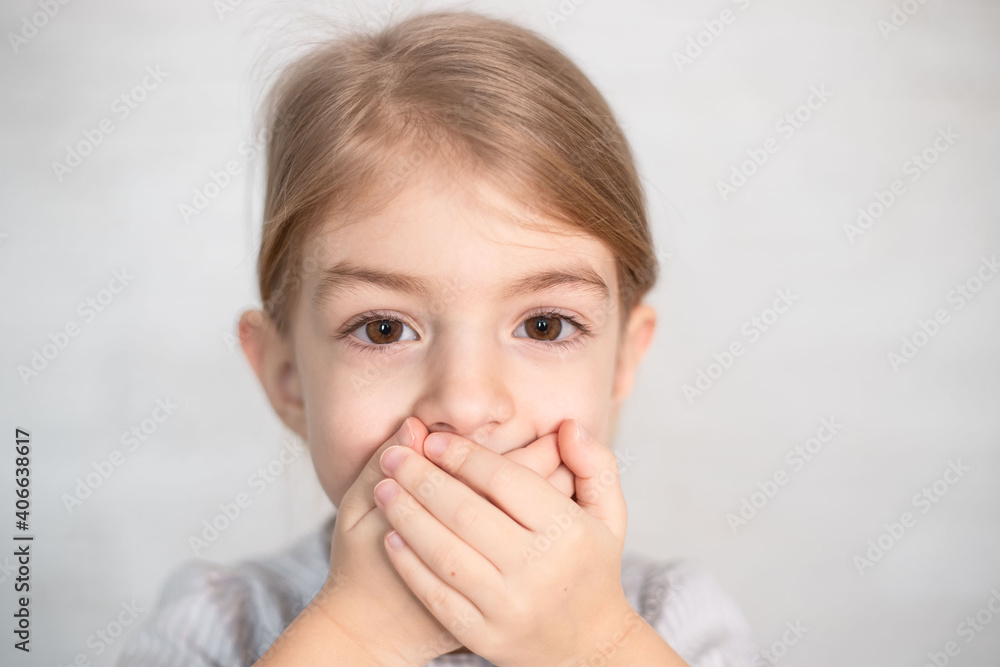 portrait of little girl, child closing his mouth with hands. Speech therapist, speech problems, stammering, mumbling. portrait of little girl, child closing his mouth with hands. Speech therapist, speech problems, stammering, mumbling.