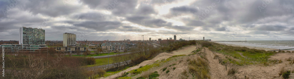 Panorama of Ostend beach, dunes and inland city view in Belgium under clouded sky