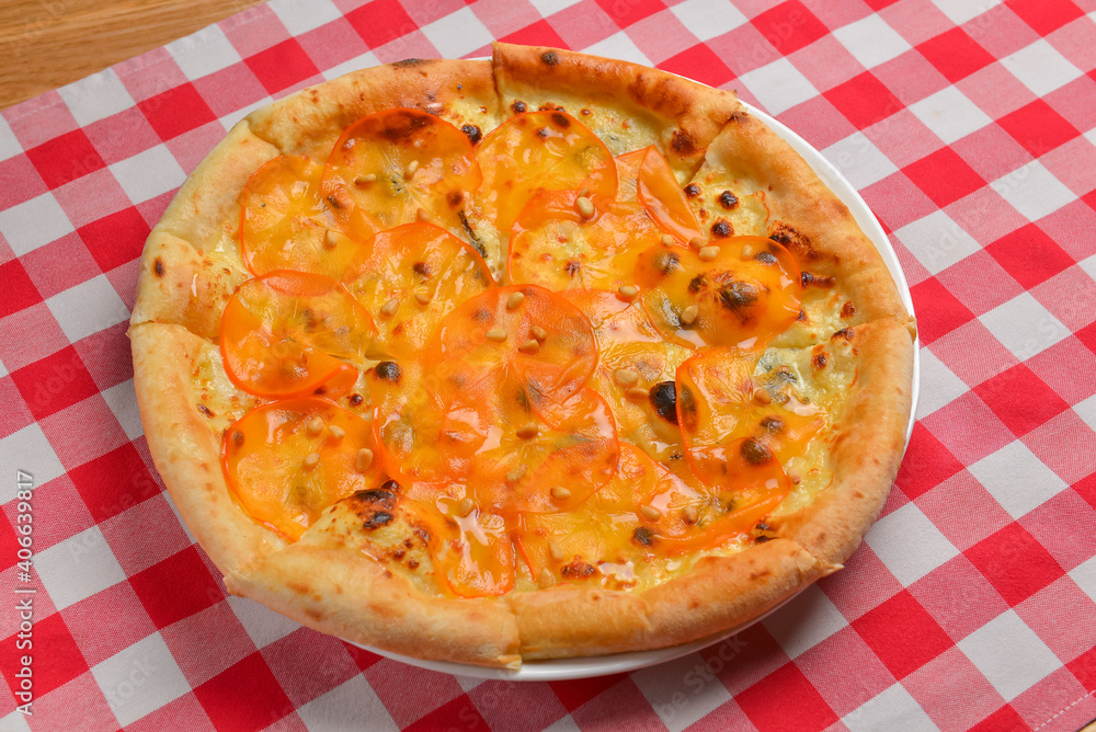 Pizza with persimmon. Italian cuisine concept flat lay, top view. Persimmon dishes menu over red plaid tablecloth. Pizza with persimmon. Italian cuisine concept flat lay, top view. Persimmon dishes menu over red plaid tablecloth.
