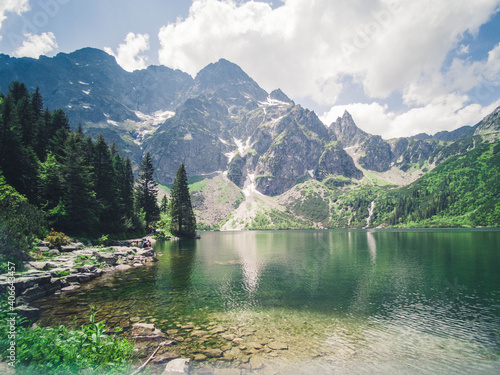 Beautiful alpine lake in the mountains, natural background, summer landscape with blue cloudy sky and reflection in crystal clear water, Morske Oko, Tatra Mountains, Zakopane, Poland