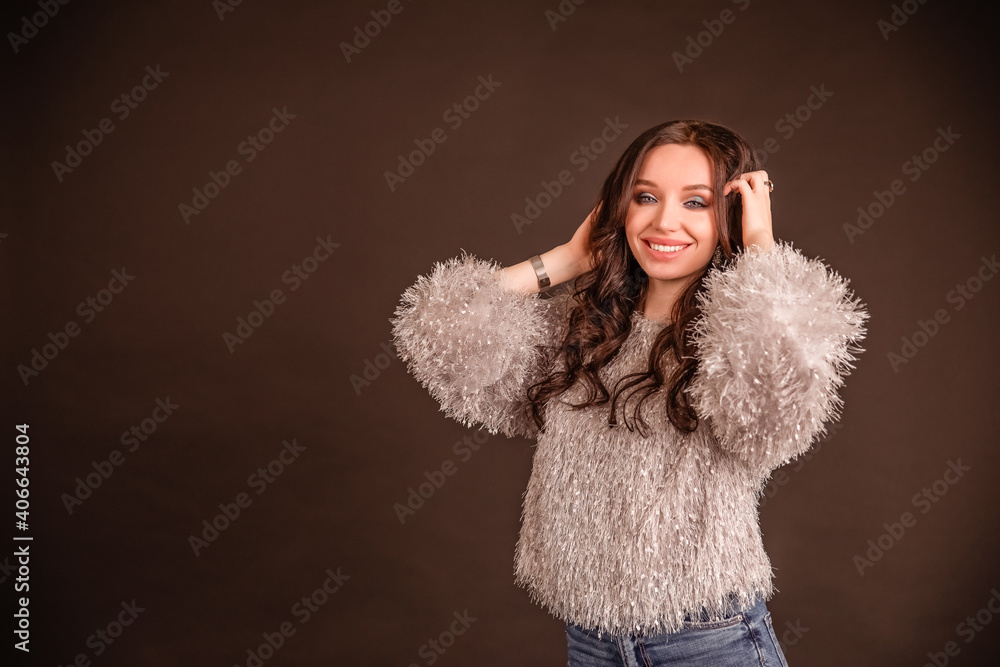 beautiful girl poses on a black gray background. lady in jeans and grey fluffy sweater beautiful girl poses on a black gray background. lady in jeans and grey fluffy sweater