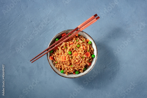 Instant noodles with chopsticks, shot from the top on a blue background