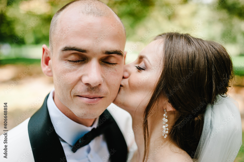 The bride and groom kissing in the park. The bride and groom kissing in the park.