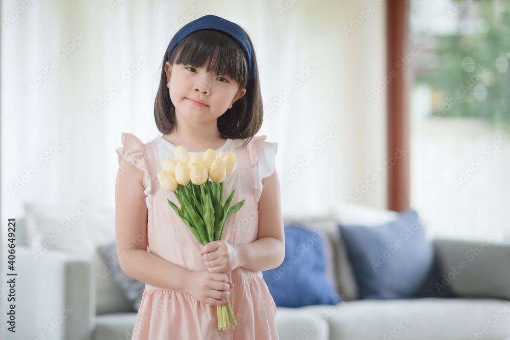 Portrait of asian little cute girl holdign flower with happy charming smile in living room at home.