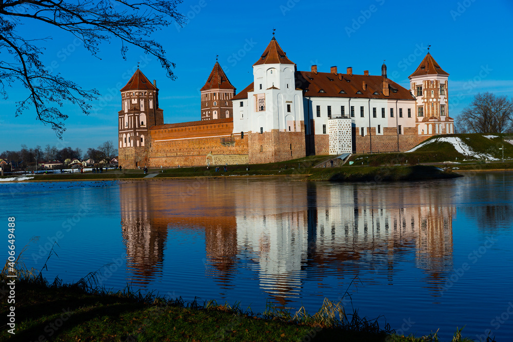 Scenic winter landscape with historic fortified Mir Castle on bank of Miranka river on sunny winter day, Belarus