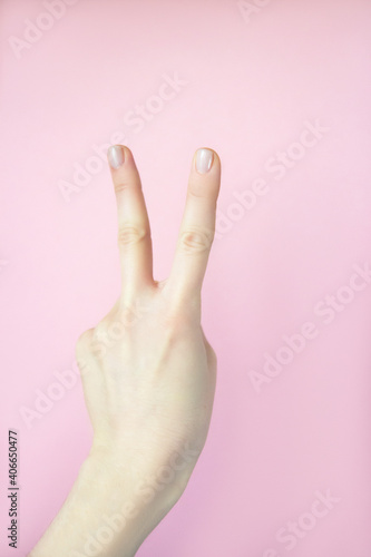 Female hand isolated on pink background. Number two index finger on pink background © Rudaieva Iryna