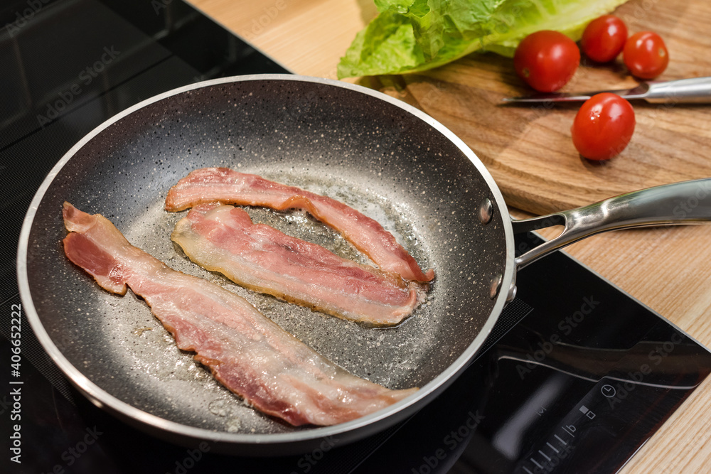 Slices of fresh fried bacon in a pan for breakfast, ingredients for chicken caesar salad, cooking on real kitchen, top view. Slices of fresh fried bacon in a pan for breakfast, ingredients for chicken caesar salad, cooking on real kitchen, top view.