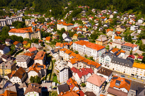 Aerial view of small town of Idrija between green hills in western Slovenia overlooking medieval Gewerkenegg Castle on sunny day photo