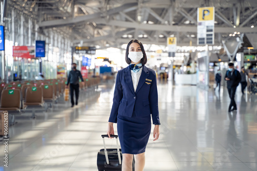 Caucasian flight attendant wearing face mask, walking in the airport.