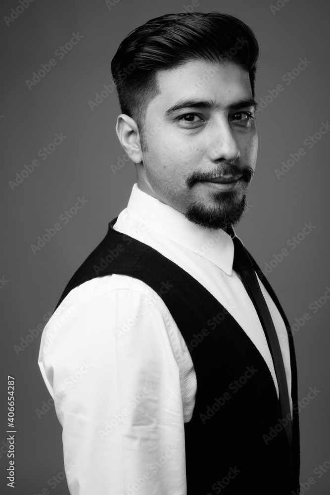 Obraz premium Young bearded Iranian businessman against gray background