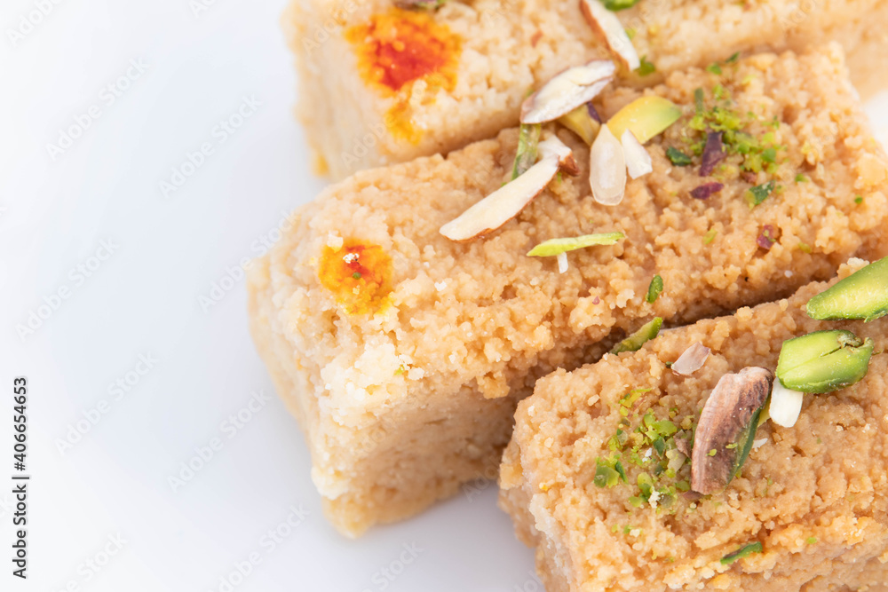 Top View Of Indian Mithai Milkcake Kalakand Burfi Or Alwar Ka Mawa Barfi Made Of Khoya Doodh Malai Decorated With Badam Or Badaam Nuts Kaju And Pista. Isolated On White Background With Space For Text Top View Of Indian Mithai Milkcake Kalakand Burfi Or Alwar Ka Mawa Barfi Made Of Khoya Doodh Malai Decorated With Badam Or Badaam Nuts Kaju And Pista. Isolated On White Background With Space For Text
