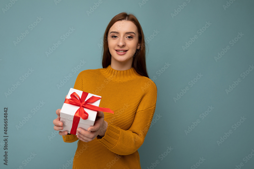 Beautiful happy young brunette woman isolated over colourful background wall wearing stylish casual clothes holding gift box and looking at camera Beautiful happy young brunette woman isolated over colourful background wall wearing stylish casual clothes holding gift box and looking at camera