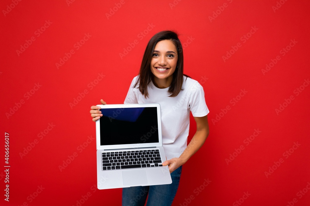 Naklejka premium Photo of beautiful young girl holding computer laptop looking at camera isolated over colourful background